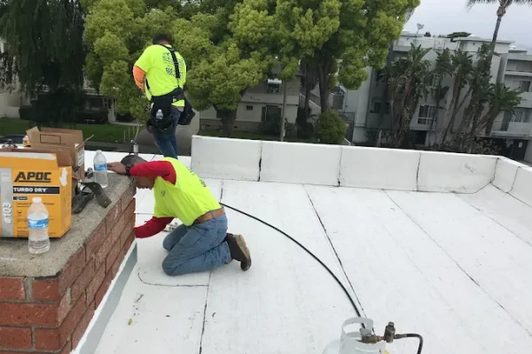 Roofing crew sealing a parapet wall on a flat roof
