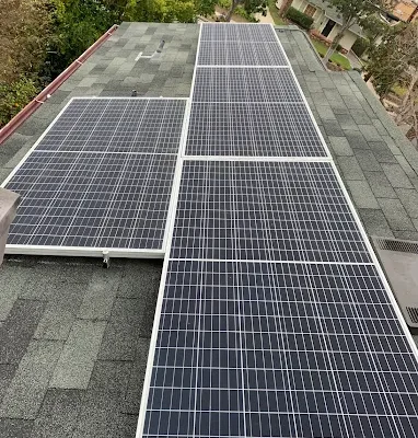 Solar panels mounted on a shingle roof surrounded by trees